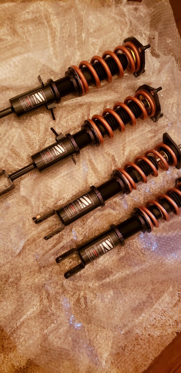 Four Stance coilovers laid out on bubble wrap